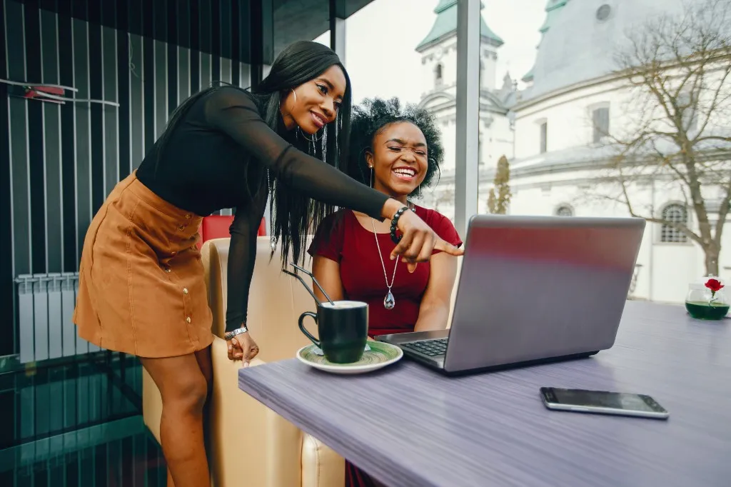 Two colleagues at a laptop, one pointing at the screen